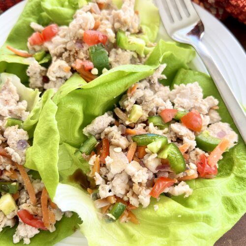 Ground turkey lettuce wraps on a plate with lots of healthy veggies